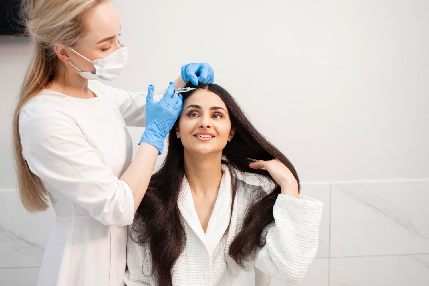 Woman receiving a scalp hair restoration treatment from a specialist wearing gloves and a mask in a clinical setting.