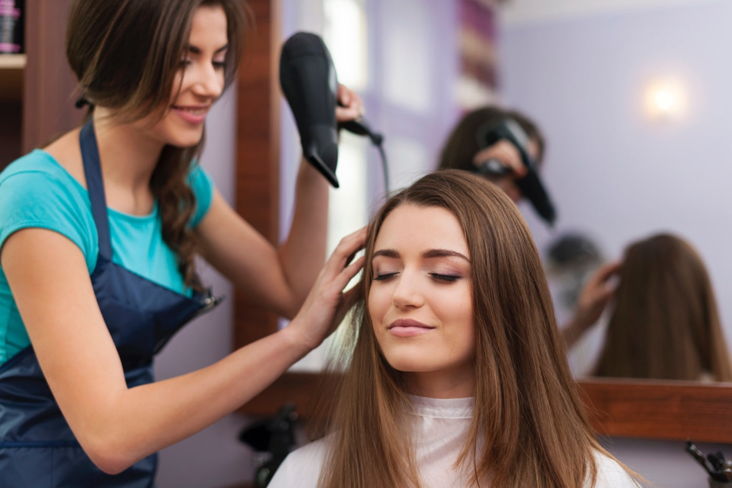 Stylist blow-drying a woman’s hair during a professional salon appointment in Boston.