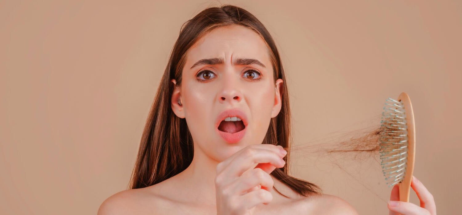 A young woman shocked to see excessive hair fall while brushing, representing hair thinning and the need for non-surgical hair loss solutions